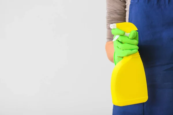 Janitor with detergent on light background — Stock Photo, Image