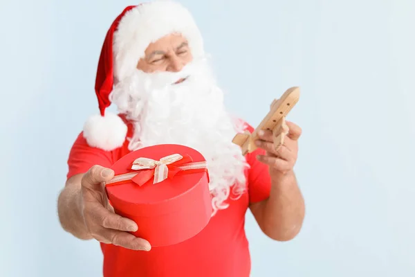 Santa Claus s hračkou letadlo a dárek na světlém pozadí. Koncept dovolené — Stock fotografie