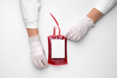 Kan nakli için beyaz arka planda kan torbası olan doktorun elleri.