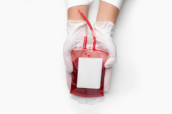 Handen van de arts met bloedverpakking voor transfusie op witte achtergrond — Stockfoto