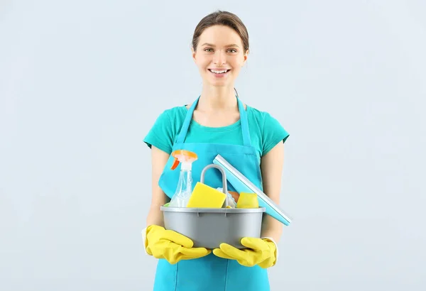 Portret van conciërge met schoonmaakbenodigdheden op lichte ondergrond — Stockfoto