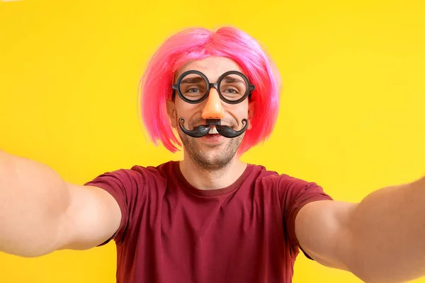 Man in funny disguise taking selfie on color background. April fools' day celebration — Stock Photo, Image