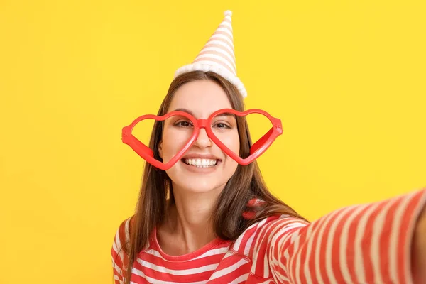 Mulher em disfarce engraçado tirar selfie no fundo de cor. Celebração do dia dos tolos de Abril — Fotografia de Stock