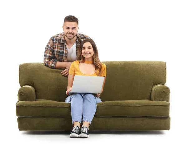 Jovem com laptop sentado no sofá e seu marido contra fundo branco — Fotografia de Stock