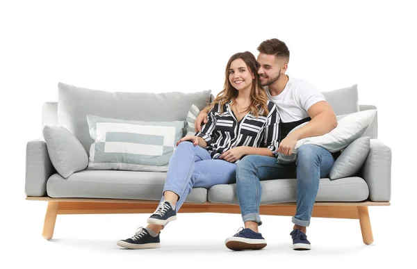 Jovem casal sentado no sofá contra fundo branco — Fotografia de Stock