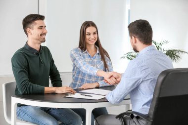 Banka müdürü ofiste bir çiftle tokalaşıyor.