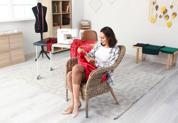 Jovem mulher costura roupas no atelier — Fotografia de Stock