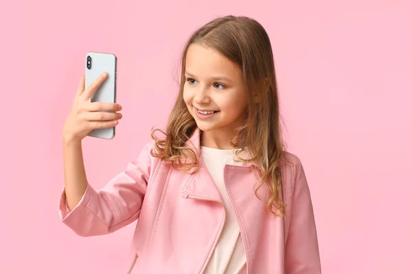 Cute little girl taking selfie on color background — Stock Photo, Image
