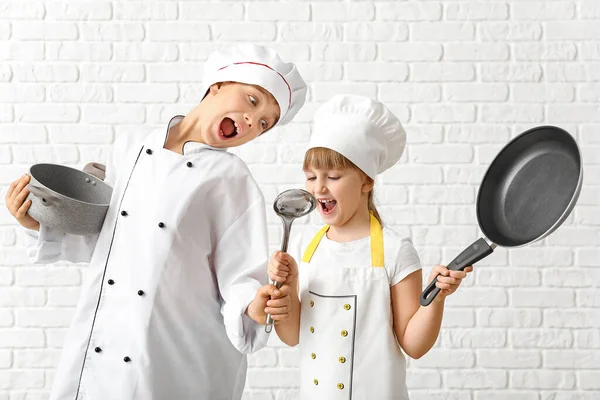 Chefs divertidos con utensilios sobre fondo de ladrillo blanco — Foto de Stock