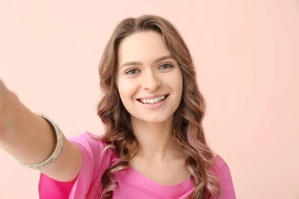 Ung kvinna som tar selfie på färg bakgrund — Stockfoto