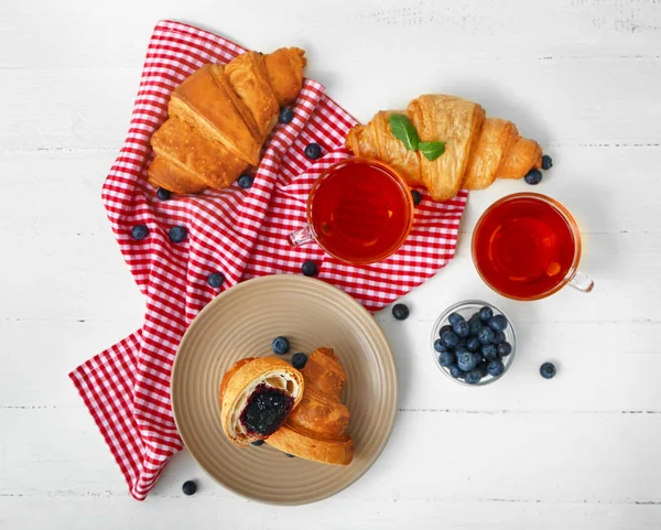 Plate with tasty sweet croissants and tea on table — Stock Photo, Image