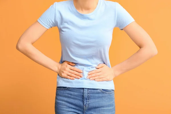 Mujer joven que sufre de calambres menstruales en el fondo de color — Foto de Stock