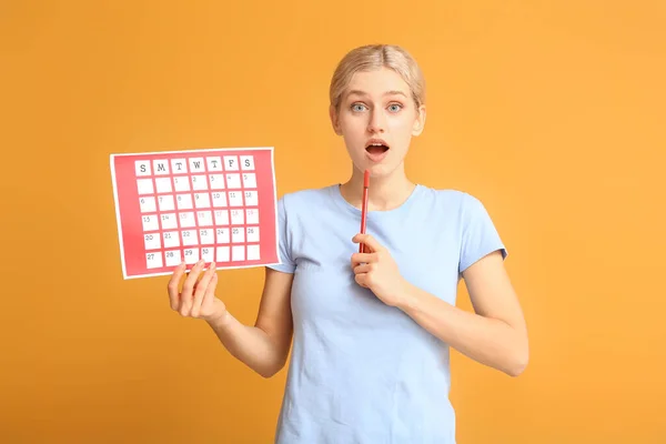 Jonge vrouw met menstruele kalender op kleur achtergrond — Stockfoto