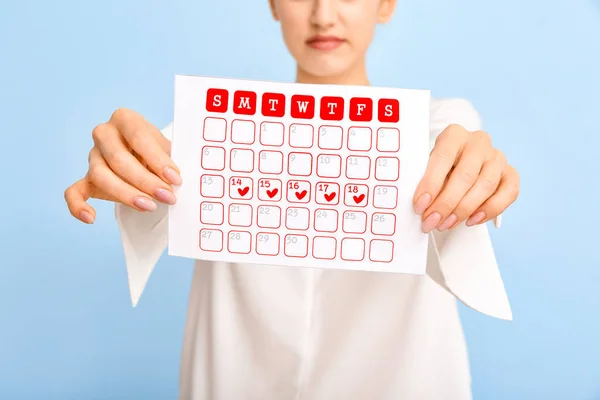 Young woman with calendar on color background. Menstruation concept — Stock Photo, Image