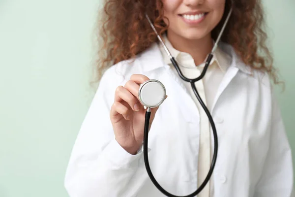 Junger afrikanisch-amerikanischer Arzt mit Stethoskop auf farbigem Hintergrund — Stockfoto
