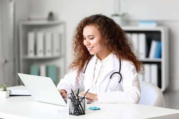 Молодий афро-американський лікар працює над ноутбуком у клініці. — стокове фото