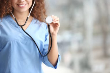 Klinikte steteskobu olan genç Afro-Amerikalı hemşire.