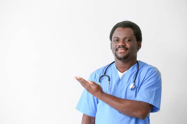 Male African-American nurse on light background — Stock Photo, Image