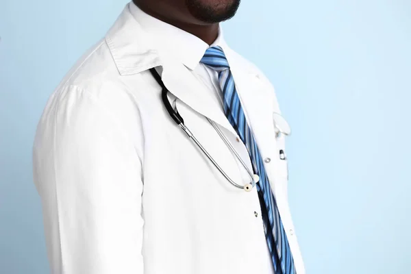 African-American doctor with stethoscope on color background — Stock Photo, Image
