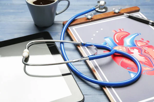 Stethoscoop met tabletcomputer en tekening van het menselijk hart op tafel — Stockfoto
