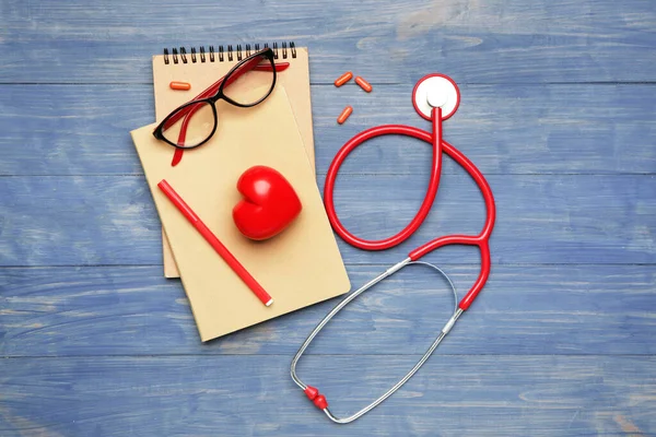 Stetoskop z sercem, notebooki i tabletki na stole — Zdjęcie stockowe