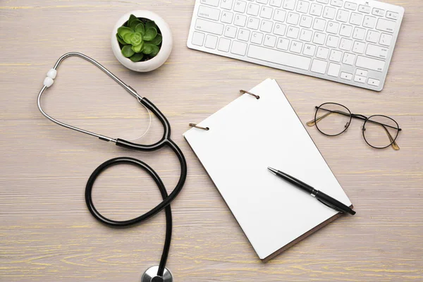 Stethoscope with computer keyboard and notebook on wooden table — Stock Photo, Image