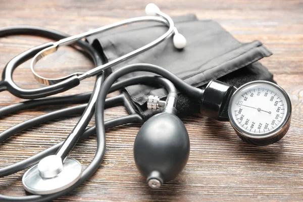 Stethoscope with sphygmomanometer on wooden background — Stock Photo, Image