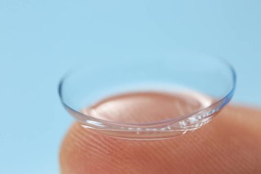 Renk arkaplanında kontakt lensli insan parmağı, yakın plan