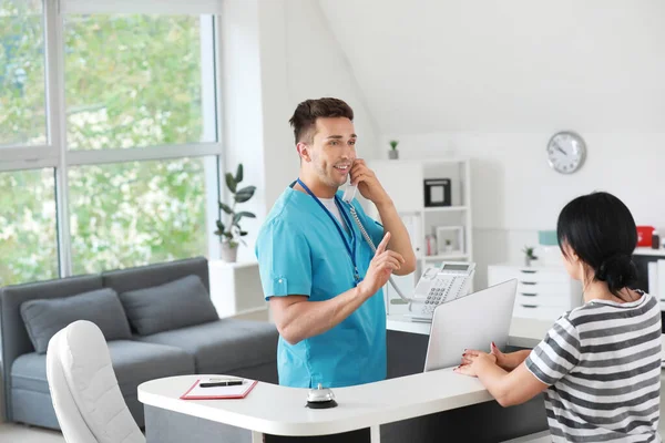 Mannelijke receptioniste werkt met patiënt in kliniek — Stockfoto