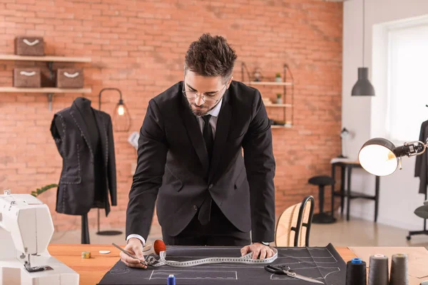 Young tailor working at table in atelier — Stockfoto