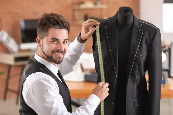 Jonge kleermaker metingen van mannelijke jas op etalagepop in atelier — Stockfoto