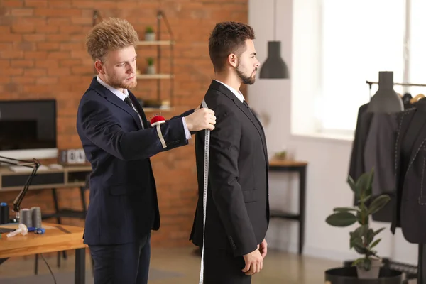 Male tailor taking client's measurements in atelier — Stock Photo, Image