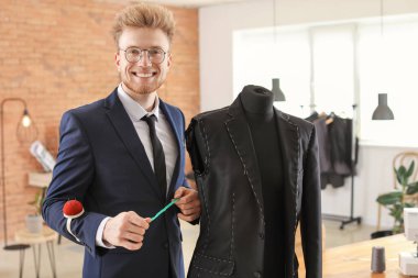 Young tailor working with mannequin in atelier