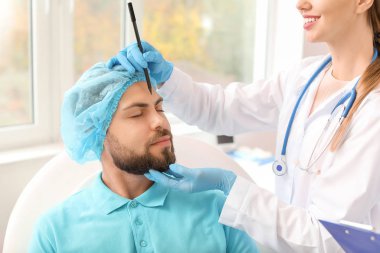 Klinikte hastanın yüzüne işaret uygulayan plastik cerrah