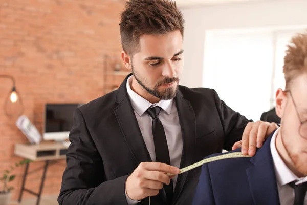 Alfaiate masculino fazendo medições do cliente no atelier — Fotografia de Stock