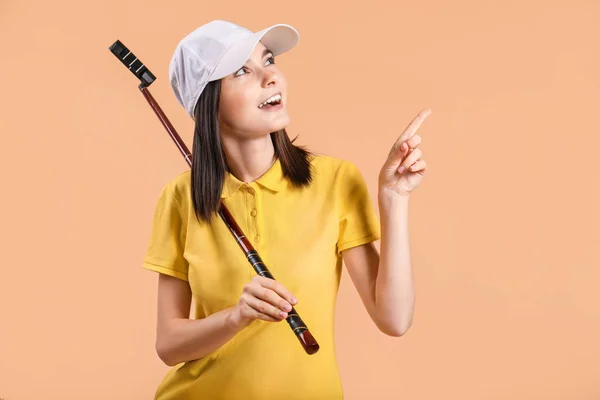 Mooie vrouwelijke golfer wijzend op iets op kleur achtergrond — Stockfoto