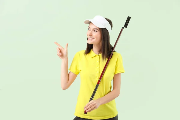 Beautiful female golfer pointing at something on color background — 스톡 사진