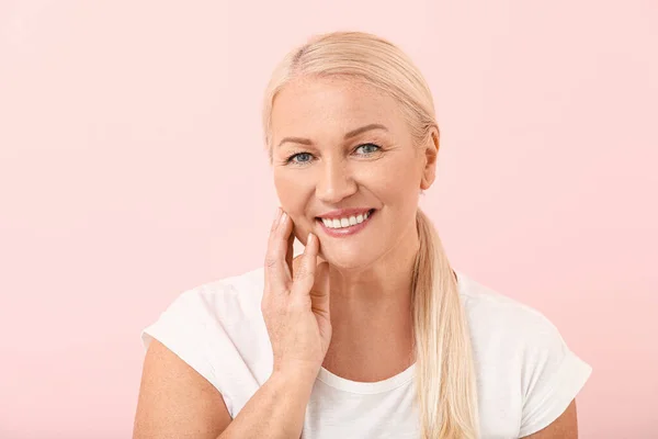 Vacker mogen kvinna med frisk hud på färg bakgrund — Stockfoto