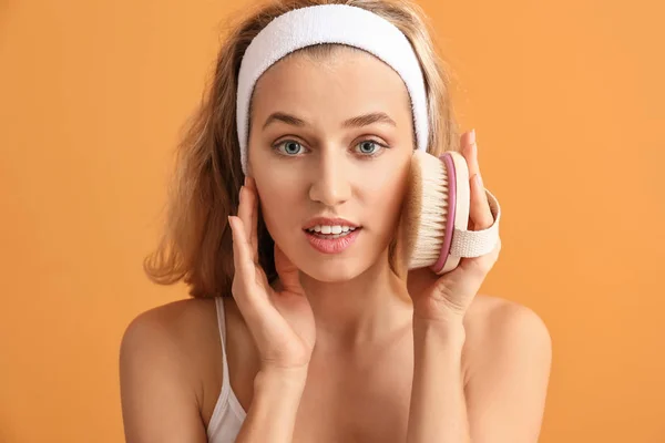 Mooie jonge vrouw met massage borstel op kleur achtergrond — Stockfoto