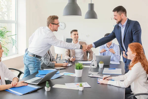 Jovens empresários apertando as mãos durante reunião no escritório — Fotografia de Stock