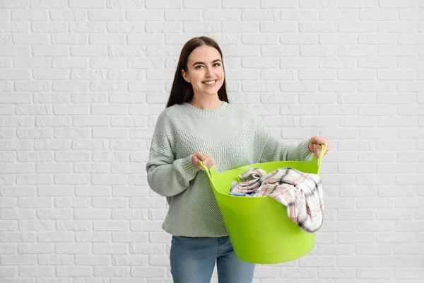 Vacker ung kvinna med tvätt på tegel bakgrund — Stockfoto