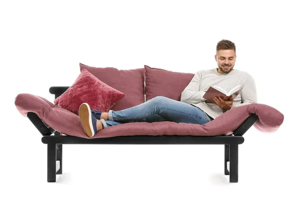 Joven hombre leyendo libro mientras se relaja en el sofá sobre fondo blanco — Foto de Stock
