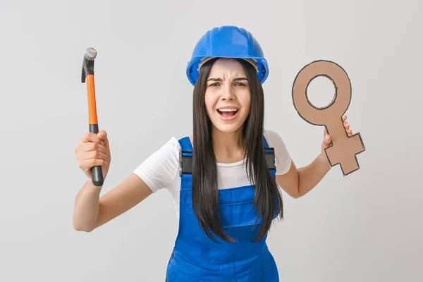 Female worker holding symbol of woman against light background. Concept of feminism — Stock Photo, Image
