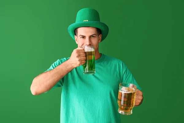 Jongeman met bier op kleur achtergrond. St. Patrick 's Day viering — Stockfoto