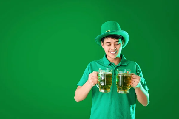 Jonge Aziatische man met bier op kleur achtergrond. St. Patrick 's Day viering — Stockfoto