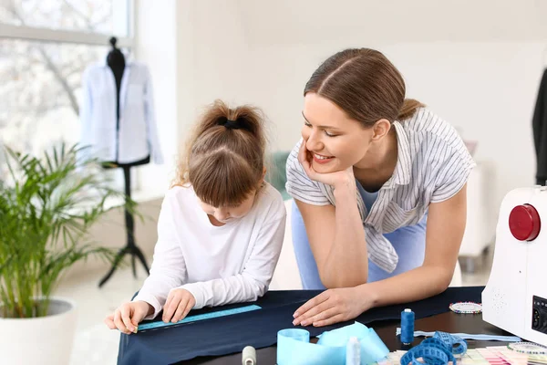 Little daughter helping her mother in tailor's workshop — Stock Photo, Image