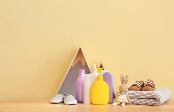 Baby clothes with cosmetics and toy on table in room — Stock Photo, Image