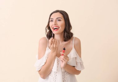 Güzel genç kadın ışık arka plan üzerinde makyaj uygulayarak