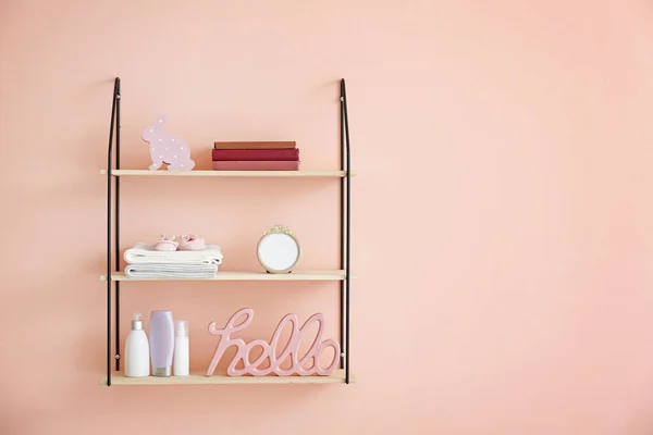 Shelves with baby accessories on color wall — Stock Photo, Image