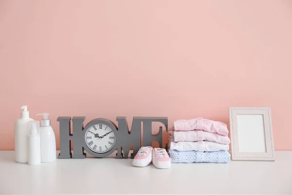 Baby clothes with cosmetics on table in room — 스톡 사진